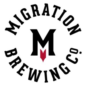 A wordmark logo for Migration Brewing appears in a circular format, mostly black and white. The word Migration appears in an arch at the top and the words "brewing co" appears in an opposite arch below. In the center, there is a capital "M" in black with a small red, directional arrow, like one that appears on a compass, below the M. 